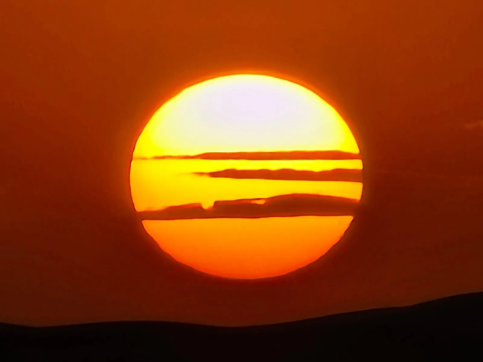 Sol enorme poniéndose en el horizonte del desierto